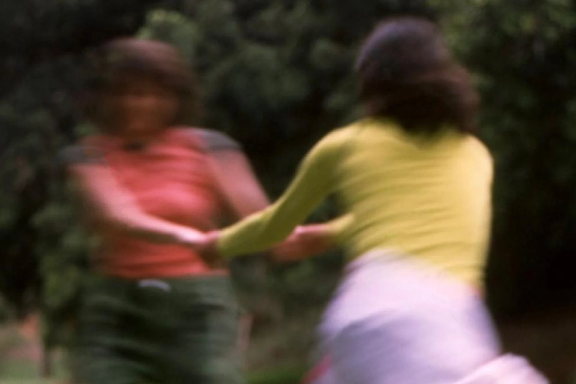 Two blurred figures holding hands and spinning outdoors