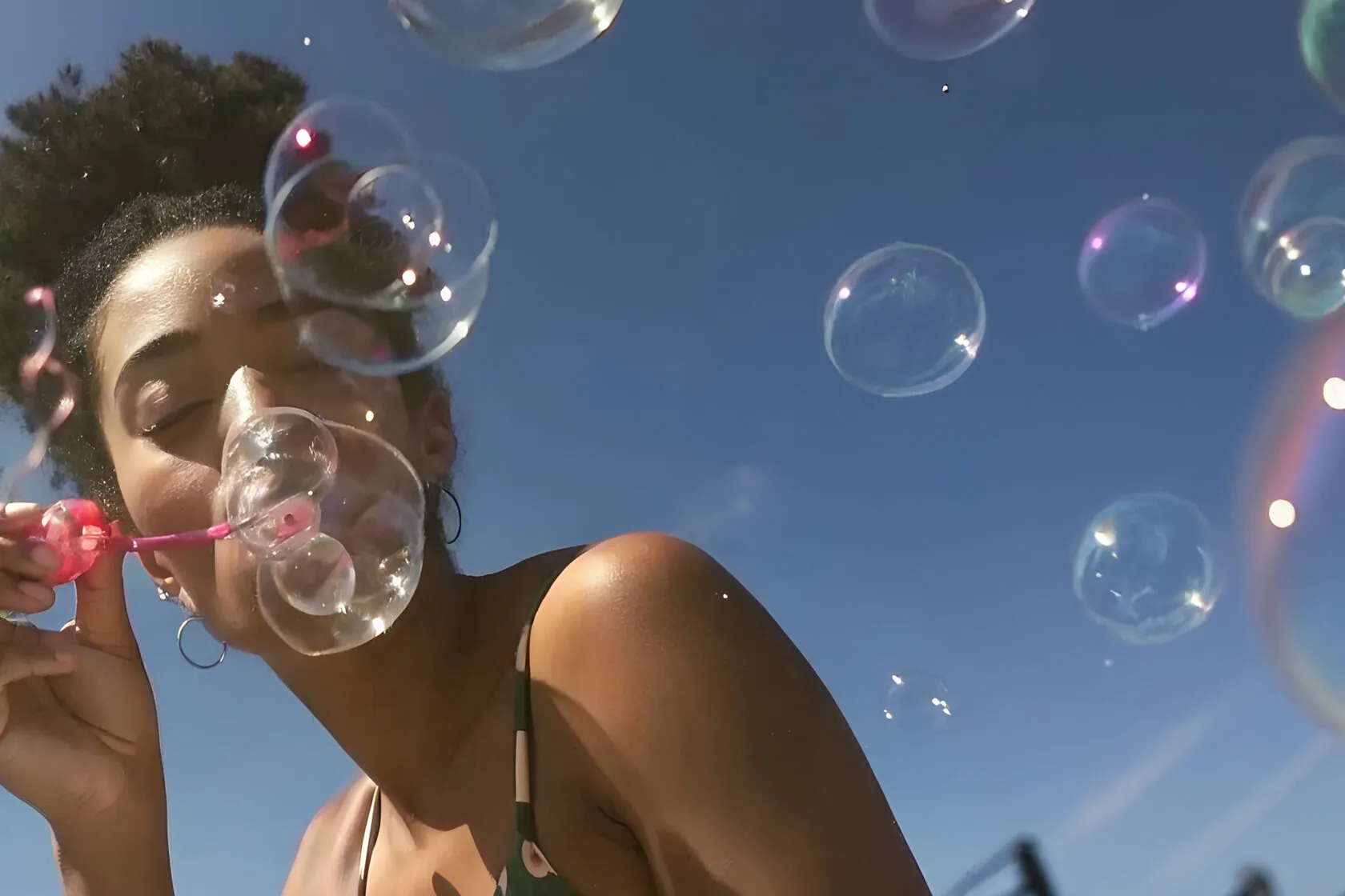 Woman blowing soap bubbles under a blue sky
