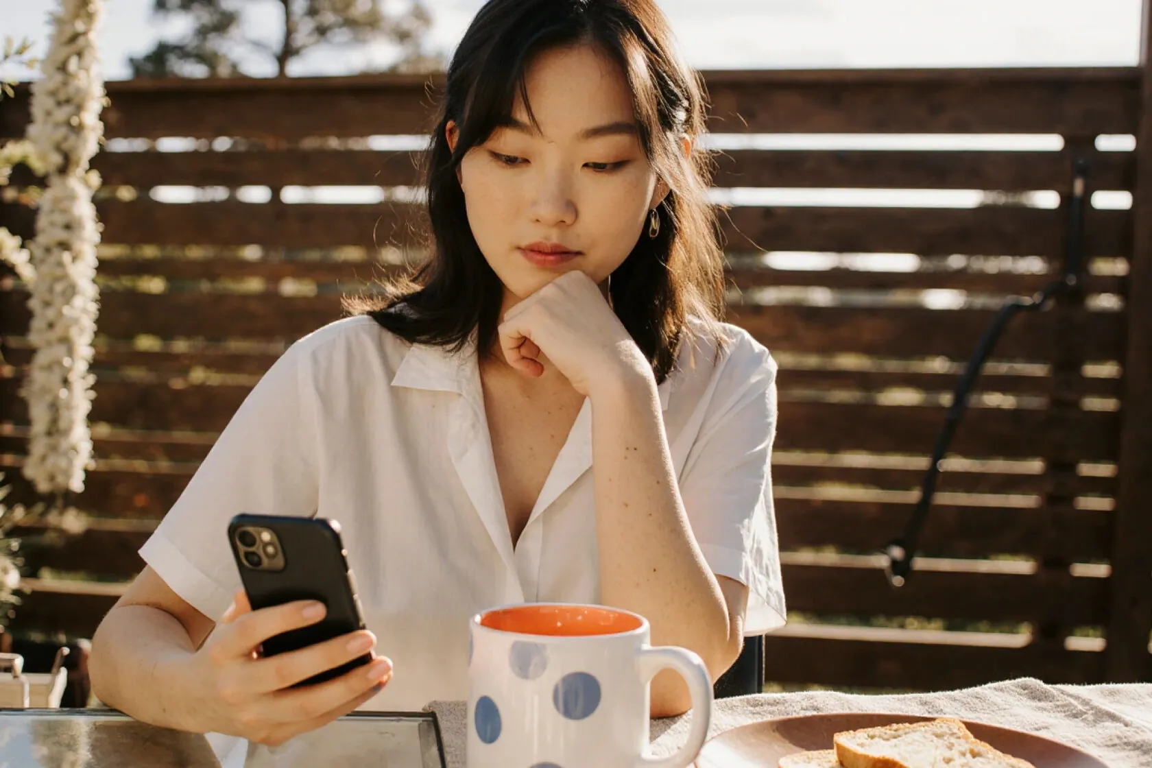 Woman reading her phone over breakfast on a sunny terrace