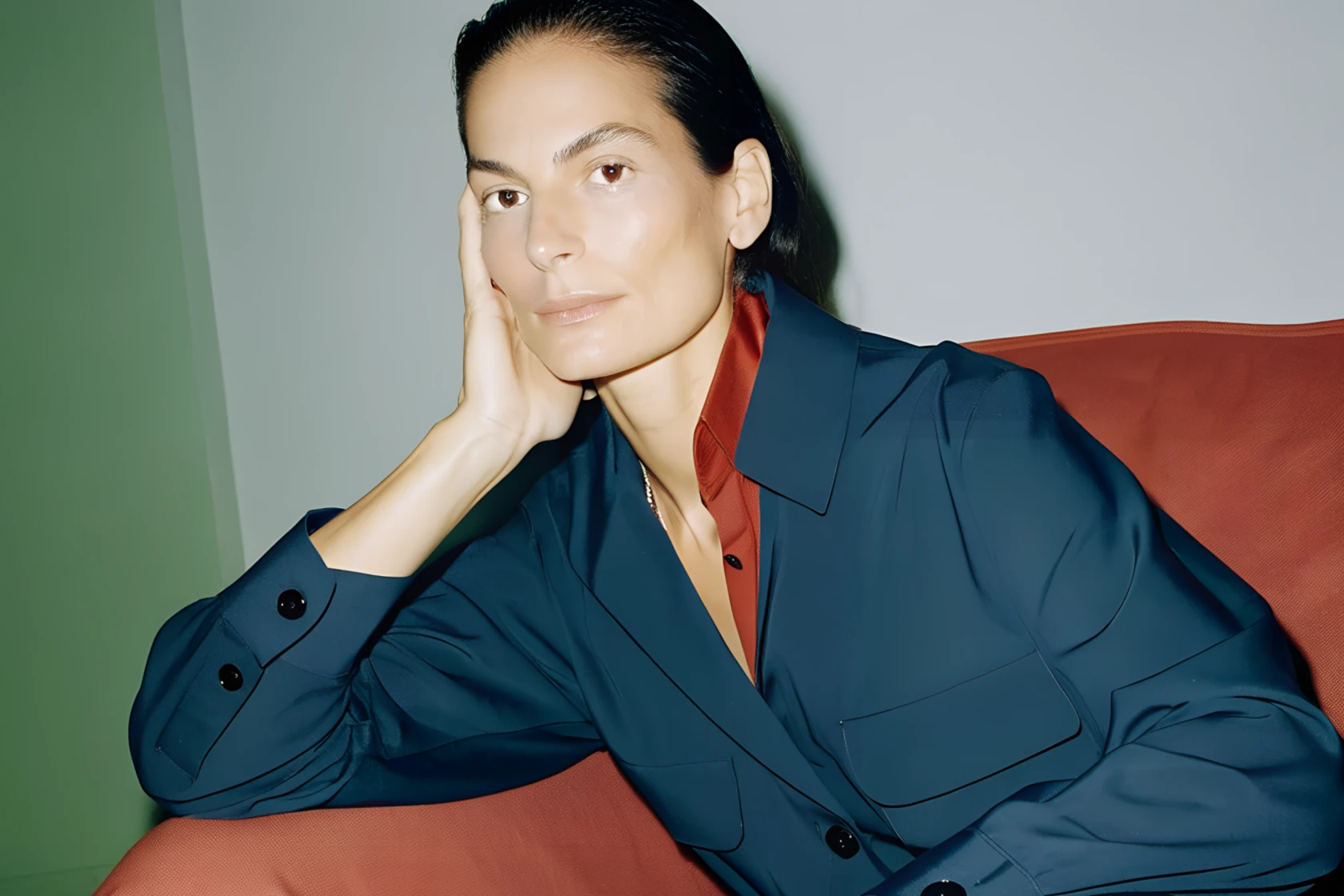 Woman in a navy shirt leaning on a red sofa